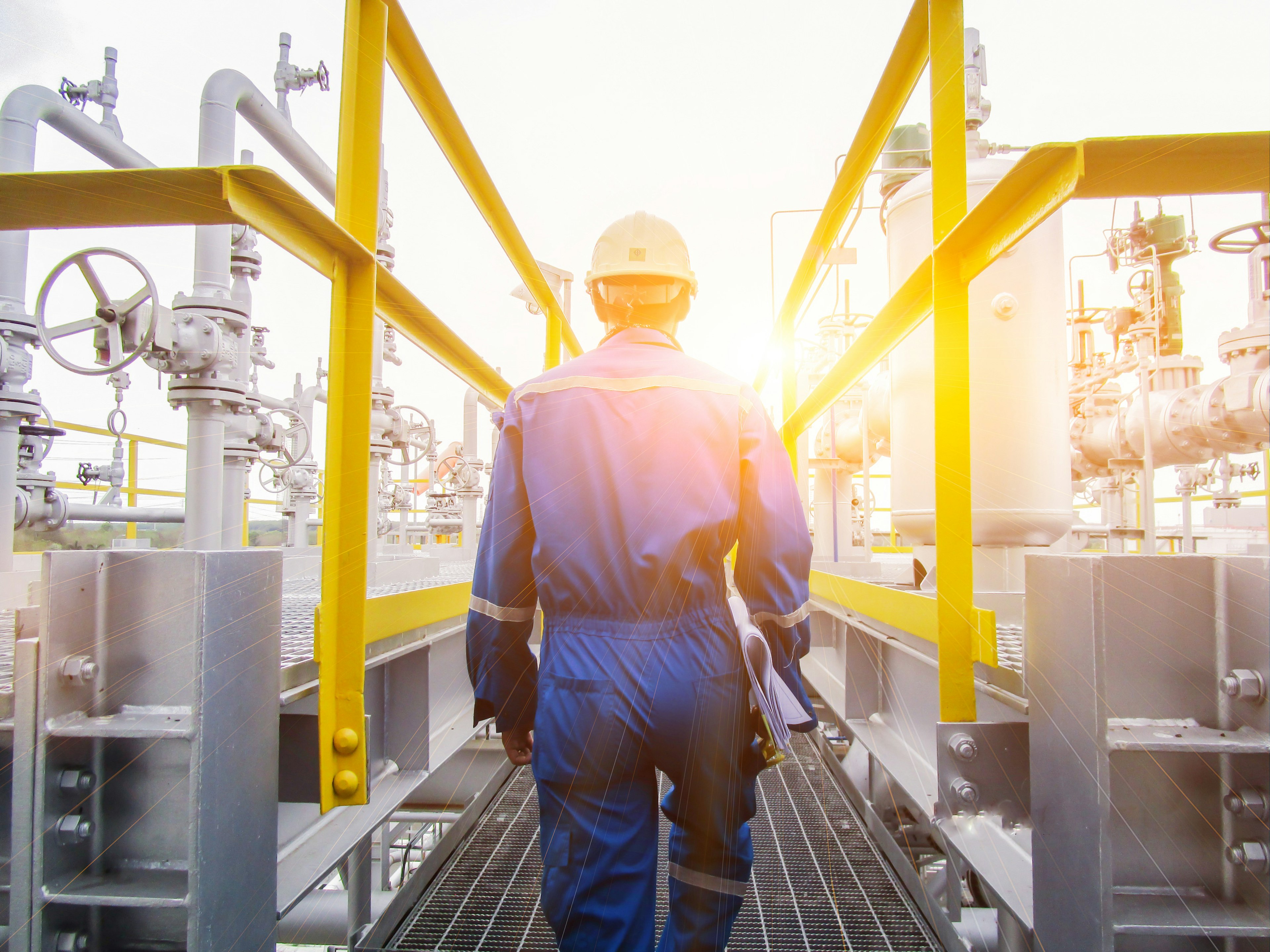 back view of engineer walking through refinery