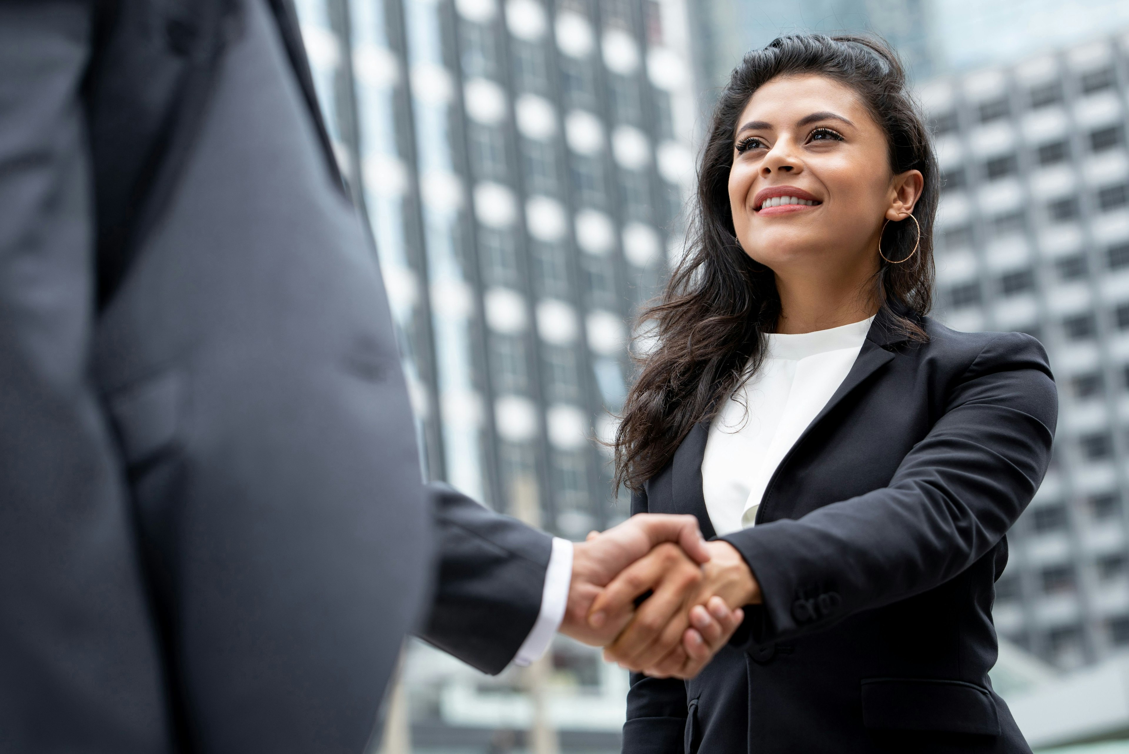 Woman Shakes Mans Hand Near Buildings